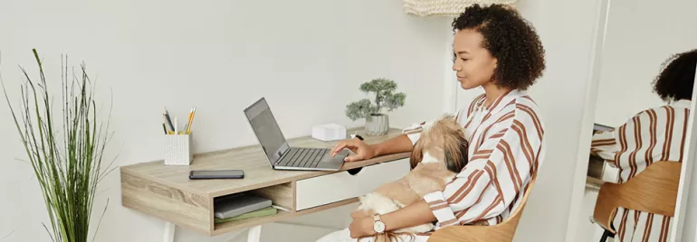 Vrouw werkt achter laptop en maakt gebruik van flexibel werkenmogelijkheden door op afstand te werken vanuit haar thuiskantoor. 